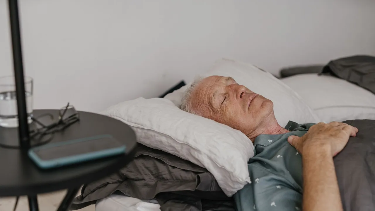 A senior man sleeps peacefully on his bed with hand on chest in a cozy bedroom setting.