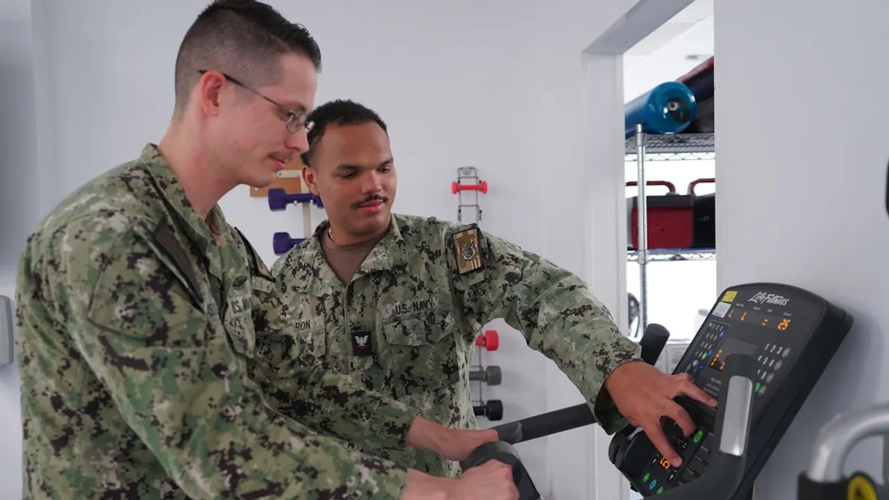Two men in military uniforms on exercise bike.