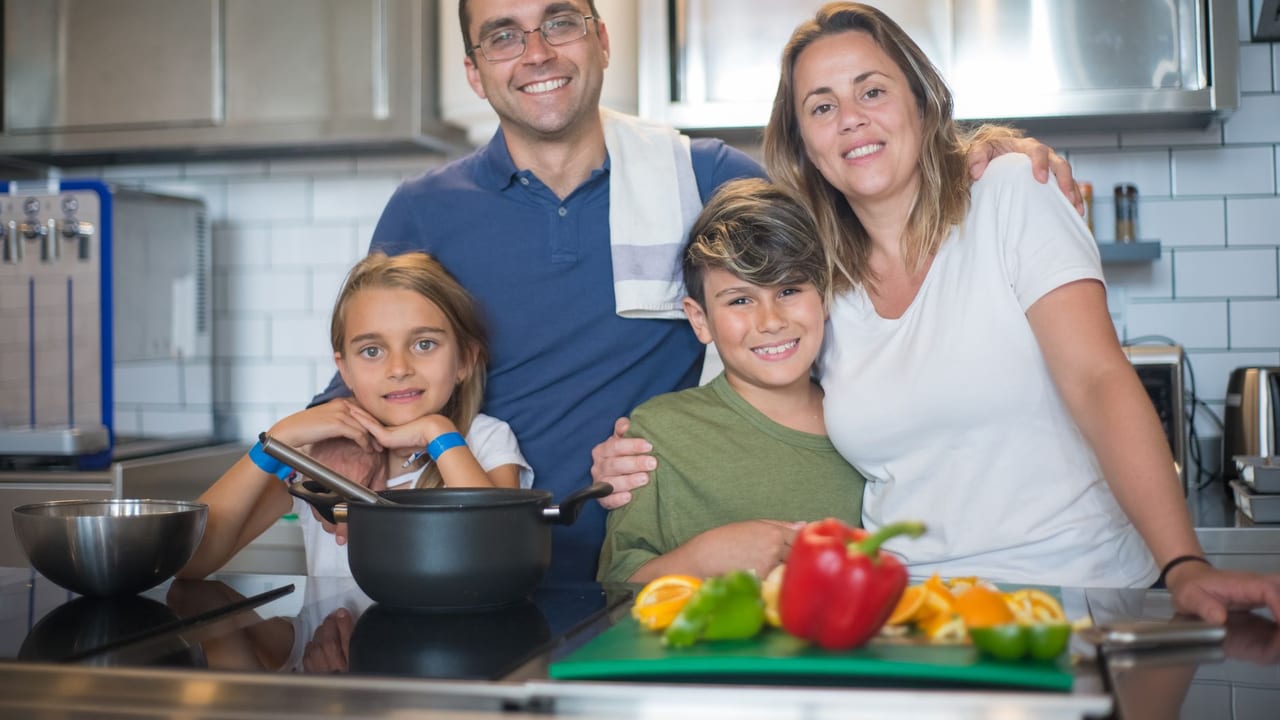 A joyful family of four cooking together in a modern kitchen, highlighting family bonding and culinary activities.