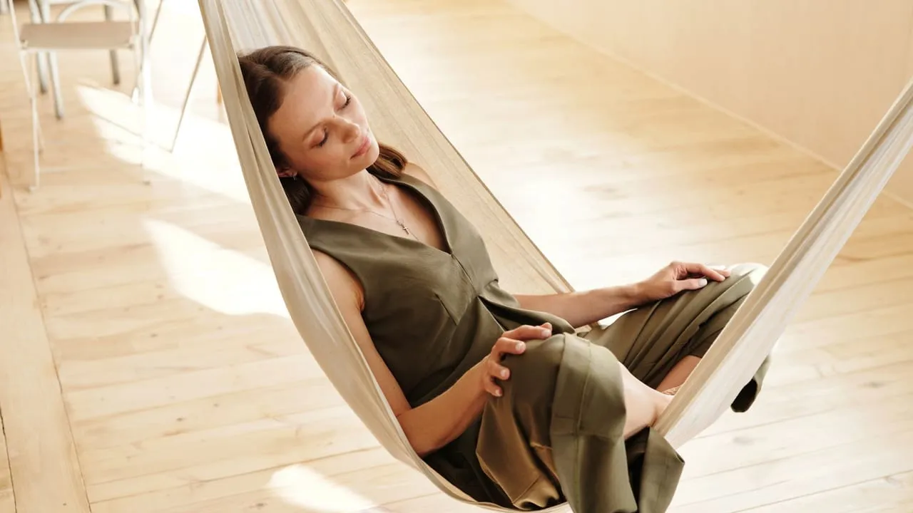A woman relaxes in a hammock indoors, embracing tranquility and leisure.