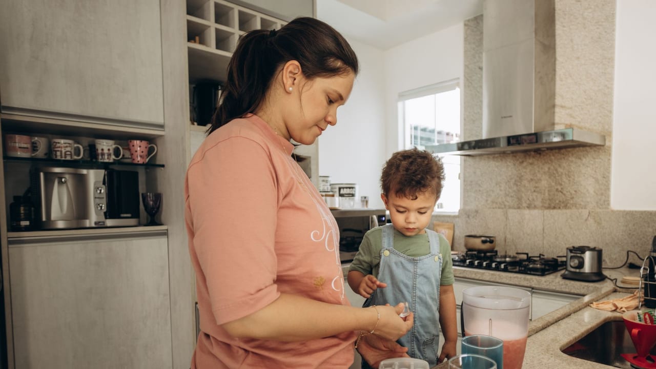 A woman and child making a smoothie in a modern kitchen, emphasizing family bonding.