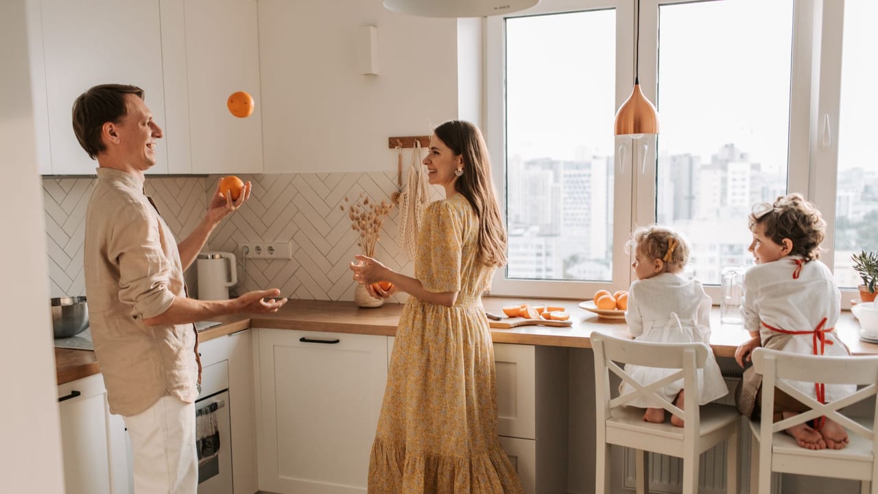 Joyful family scene with parents and children playing in a bright kitchen.
