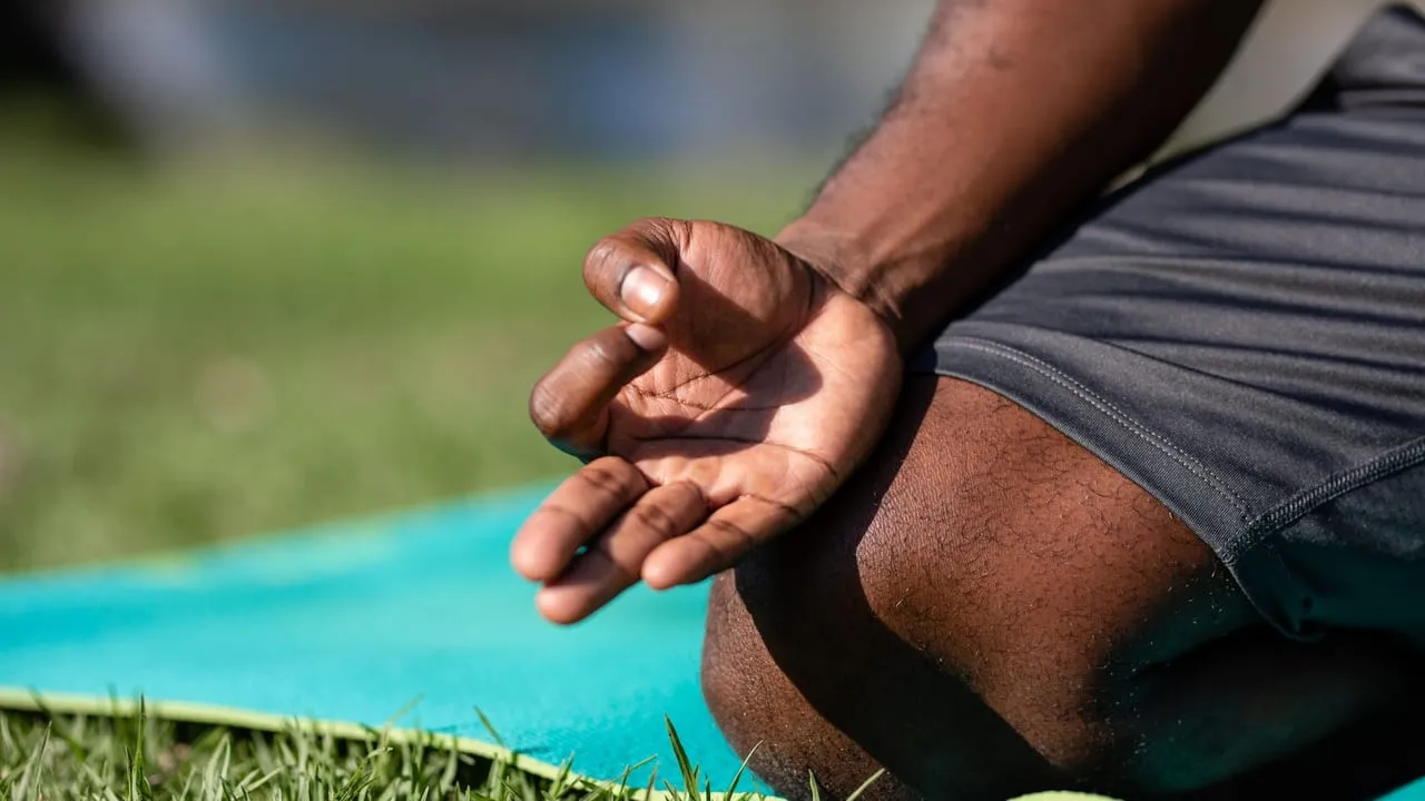Focused meditation hand gesture on a blue yoga mat outdoors, highlighting mindfulness.