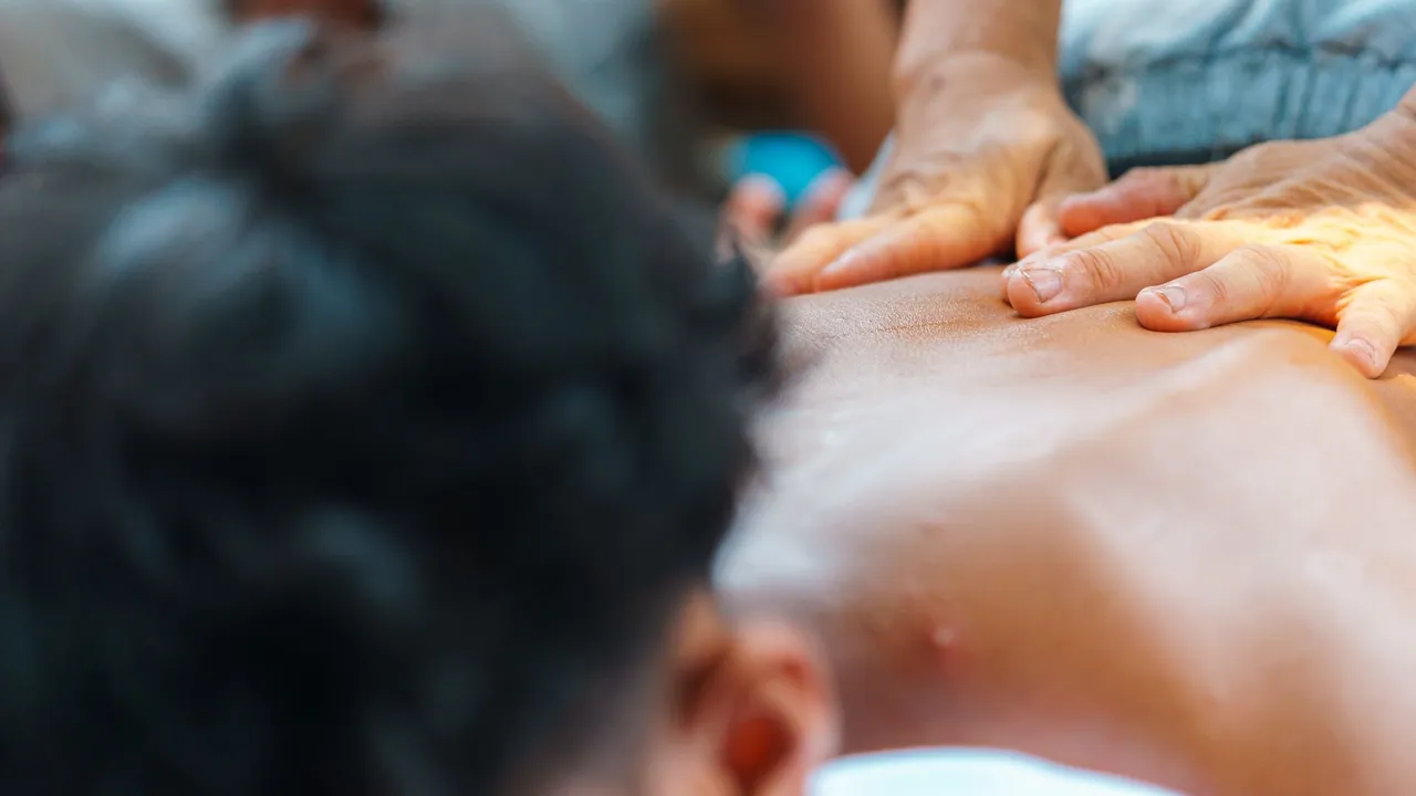 Close-up view of hands performing a relaxing massage therapy session on a person's back, promoting relaxation.