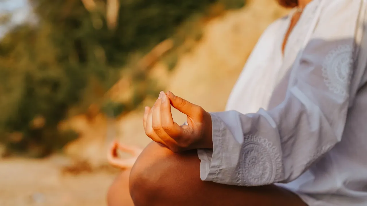 A close-up of a person meditating outdoors, capturing mindfulness at sunset on a beach.