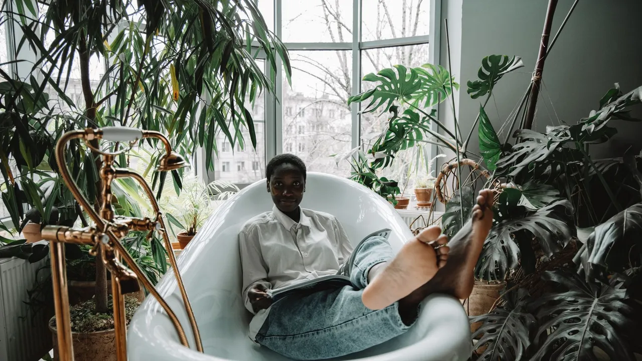 A woman enjoys a relaxing moment reading in a bathtub, surrounded by lush indoor plants.