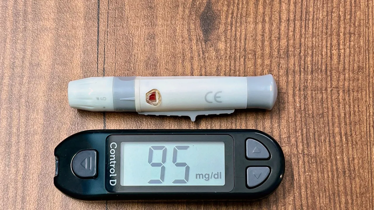 Close-up of a glucometer reading 95 mg/dl with a lancing device, ideal for diabetes and healthcare imagery.