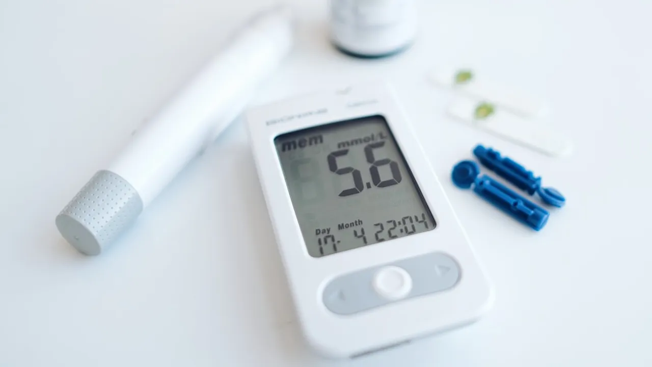 A blood glucose meter with a lancing device and test strips on white