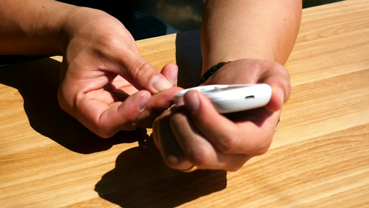 a person sitting at a table holding a cell phone