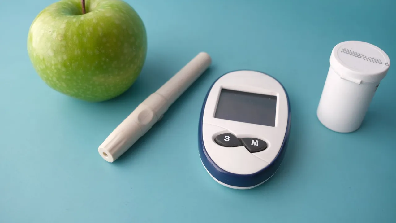 Flat lay of a glucose monitor, apple, and insulin pen on a pastel background.