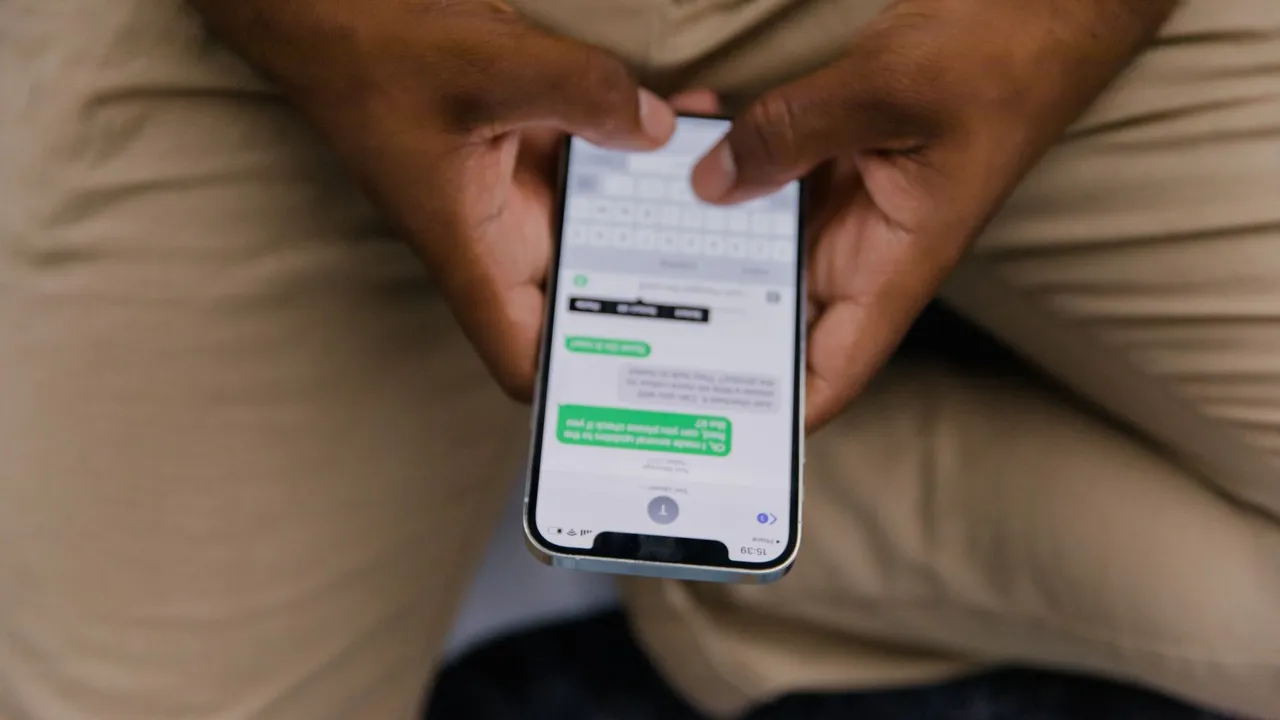 Close-up view of hands texting on a smartphone, focusing on the screen displaying messages.